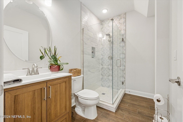 bathroom with hardwood / wood-style floors, vanity, vaulted ceiling, toilet, and an enclosed shower