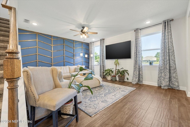 living room with hardwood / wood-style floors, ceiling fan, and a textured ceiling