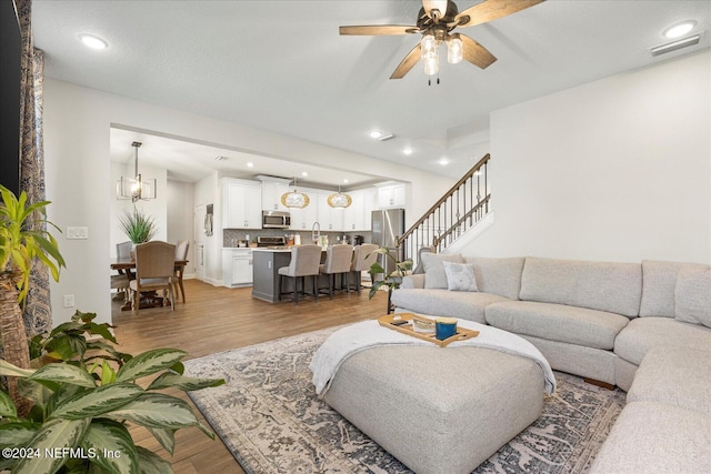 living room featuring a textured ceiling, ceiling fan with notable chandelier, and hardwood / wood-style flooring