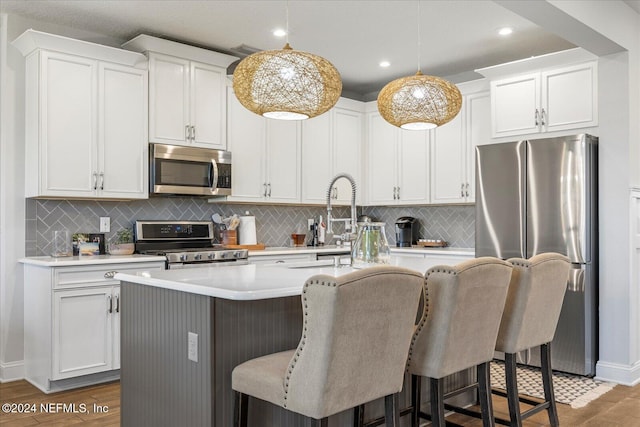 kitchen with stainless steel appliances, an island with sink, and dark wood-type flooring