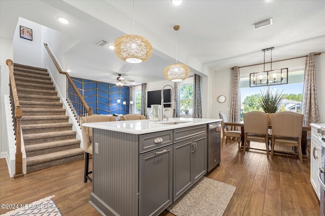 kitchen with a center island with sink, decorative light fixtures, dark hardwood / wood-style flooring, and dishwasher