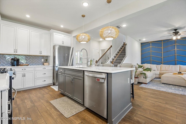 kitchen featuring appliances with stainless steel finishes, white cabinetry, hanging light fixtures, and dark wood-type flooring