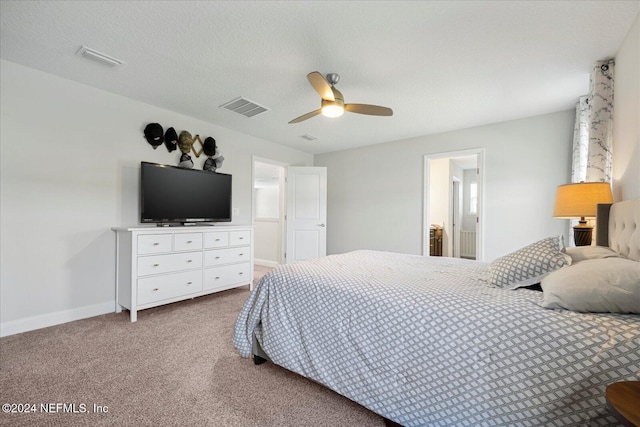 carpeted bedroom featuring a textured ceiling, ensuite bathroom, and ceiling fan