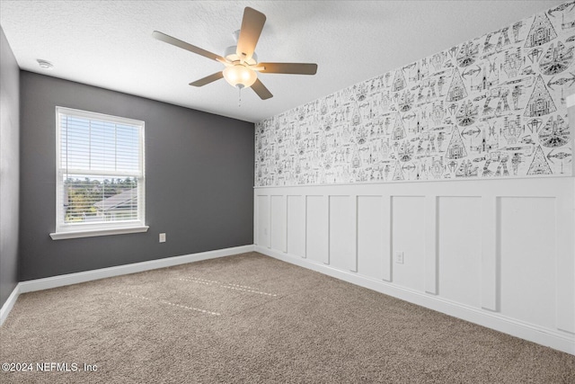 unfurnished room featuring ceiling fan, light colored carpet, and a textured ceiling