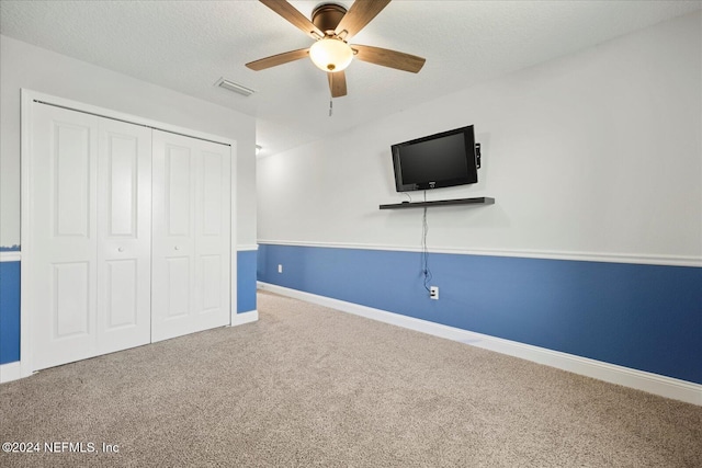 unfurnished bedroom with carpet, ceiling fan, a textured ceiling, and a closet