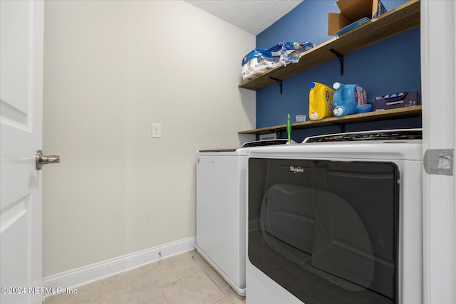 washroom featuring washer and clothes dryer, light tile patterned floors, and a textured ceiling