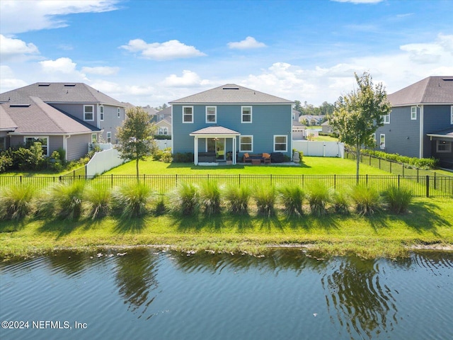 rear view of house with a water view and a yard