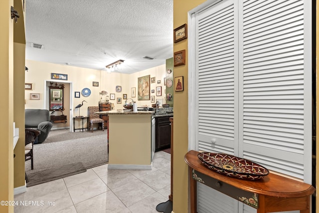 kitchen featuring light tile patterned flooring, dark stone countertops, kitchen peninsula, and a textured ceiling