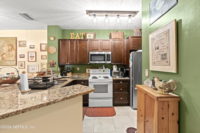 kitchen with light stone countertops, sink, stainless steel appliances, a textured ceiling, and light tile patterned flooring