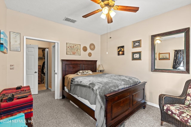 bedroom featuring light carpet, a textured ceiling, and ceiling fan