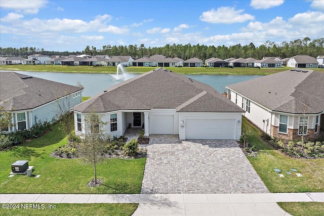 view of front of home featuring a front yard, a water view, and a garage