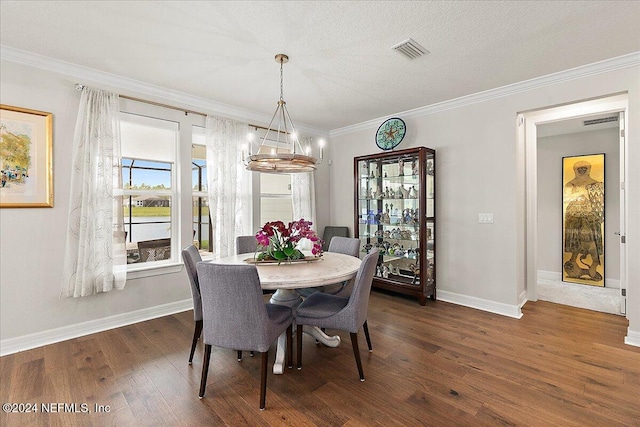 dining space featuring a textured ceiling, dark hardwood / wood-style floors, crown molding, and a chandelier