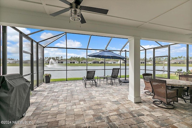 view of patio with a lanai, grilling area, ceiling fan, and a water view