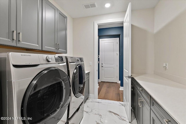 clothes washing area featuring washer and clothes dryer and cabinets