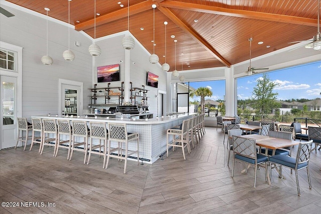 kitchen with pendant lighting, high vaulted ceiling, a healthy amount of sunlight, wood ceiling, and a breakfast bar area