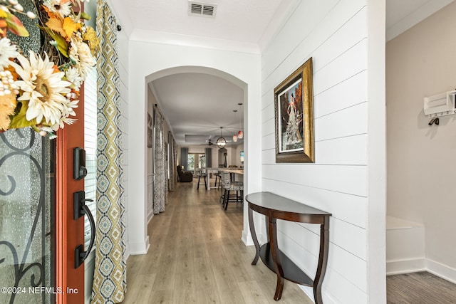 corridor with light hardwood / wood-style flooring and crown molding