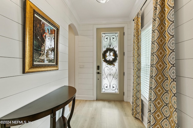 foyer featuring ornamental molding, light hardwood / wood-style flooring, and a healthy amount of sunlight