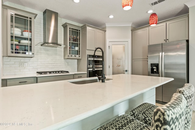 kitchen featuring stainless steel appliances, wall chimney range hood, backsplash, decorative light fixtures, and gray cabinets