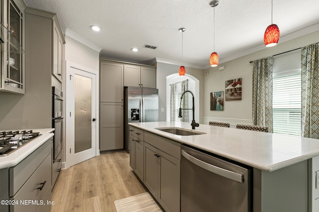 kitchen featuring pendant lighting, a center island with sink, sink, gray cabinets, and appliances with stainless steel finishes