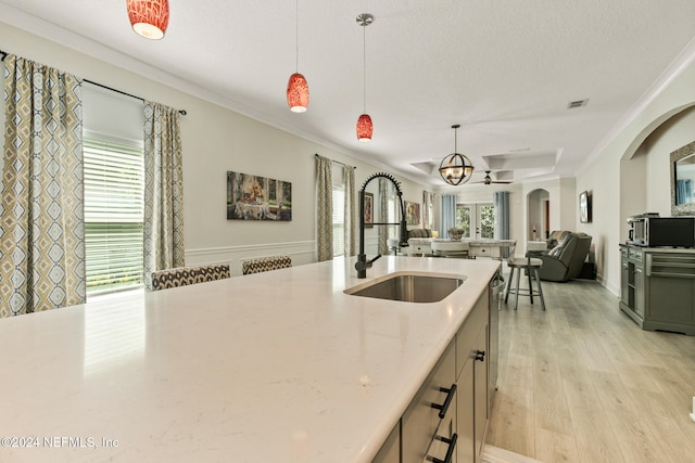 kitchen featuring sink, light hardwood / wood-style flooring, crown molding, a textured ceiling, and decorative light fixtures