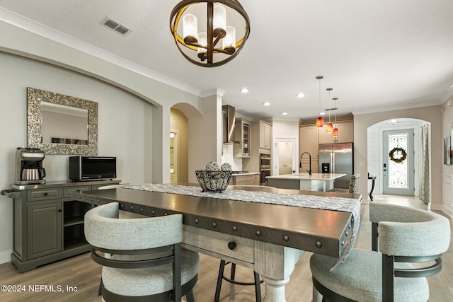 dining room with crown molding, sink, a chandelier, and hardwood / wood-style flooring