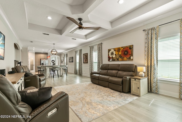 living room with ceiling fan, coffered ceiling, light hardwood / wood-style flooring, beamed ceiling, and crown molding