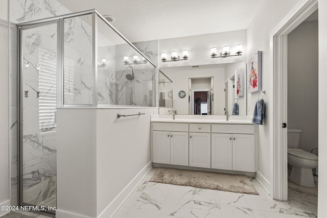 bathroom with vanity, toilet, a shower with shower door, and a textured ceiling