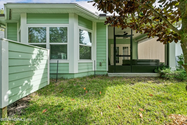 view of property exterior featuring a lawn, a sunroom, and ceiling fan