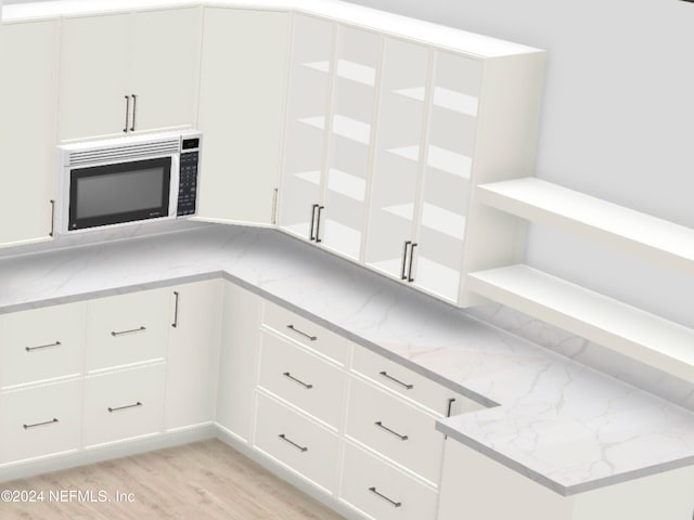 kitchen featuring light stone countertops and white cabinetry