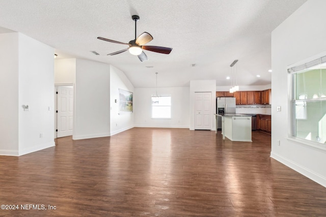 unfurnished living room featuring dark hardwood / wood-style floors, ceiling fan, a textured ceiling, and vaulted ceiling