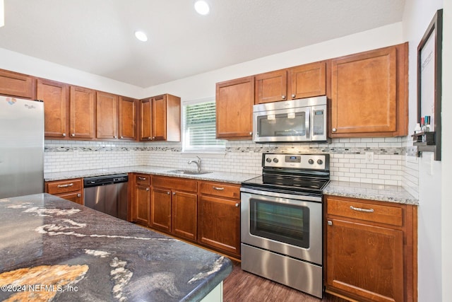 kitchen featuring stone counters, appliances with stainless steel finishes, dark wood-type flooring, and sink