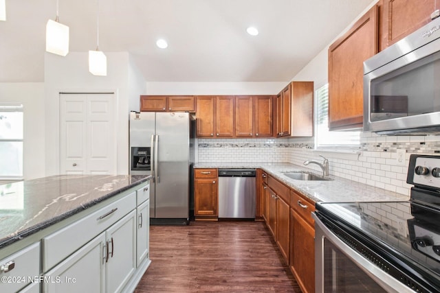 kitchen featuring light stone counters, stainless steel appliances, sink, pendant lighting, and dark hardwood / wood-style floors