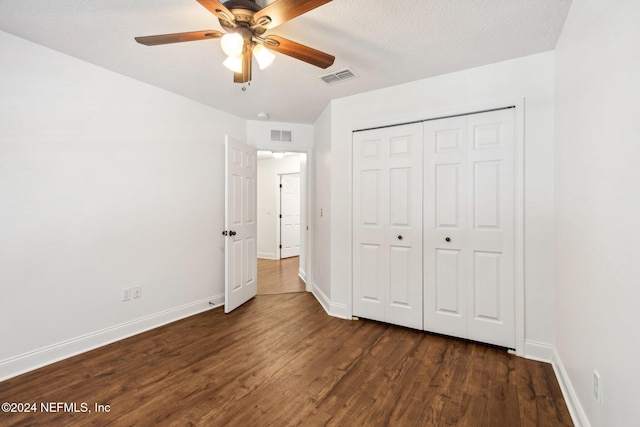 unfurnished bedroom with a textured ceiling, a closet, ceiling fan, and dark wood-type flooring