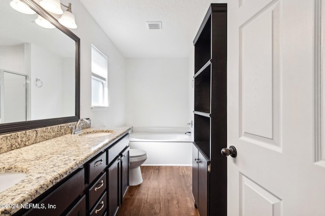 full bathroom featuring wood-type flooring, a textured ceiling, shower with separate bathtub, toilet, and vanity