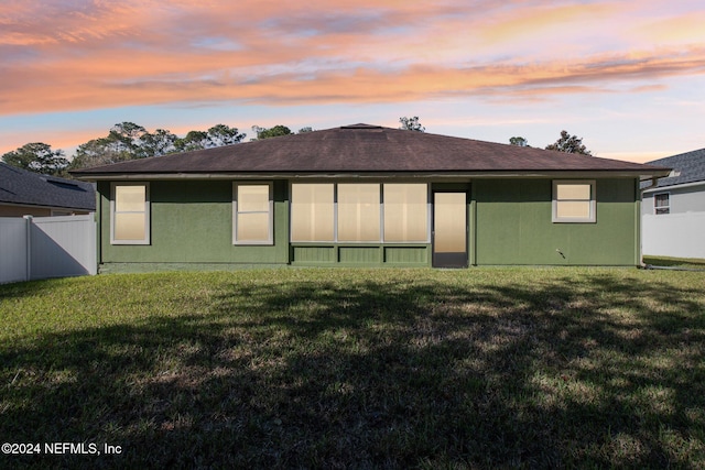 back house at dusk featuring a yard