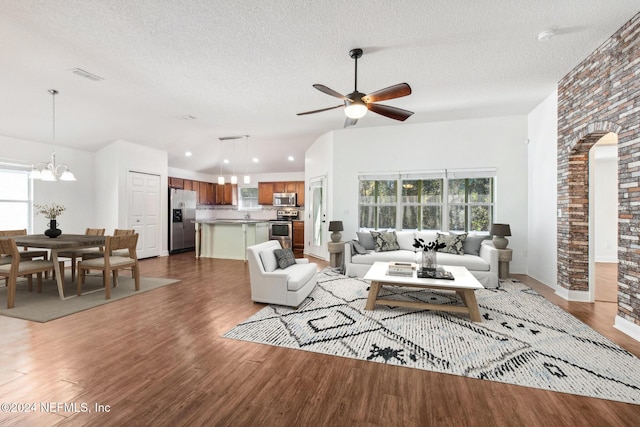 living room with plenty of natural light, dark hardwood / wood-style flooring, a textured ceiling, and ceiling fan with notable chandelier