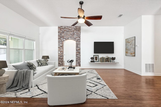 living room with ceiling fan, dark wood-type flooring, and a textured ceiling