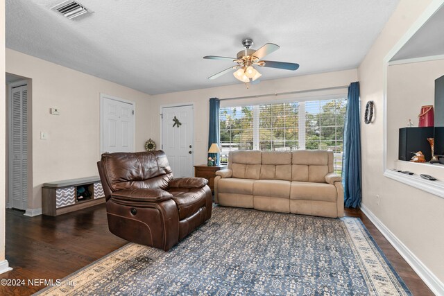 living room with ceiling fan, dark hardwood / wood-style flooring, and a textured ceiling