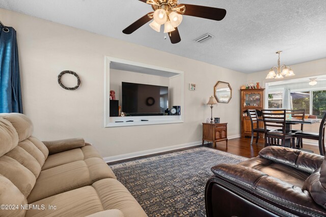 living room with ceiling fan with notable chandelier, dark hardwood / wood-style flooring, and a textured ceiling