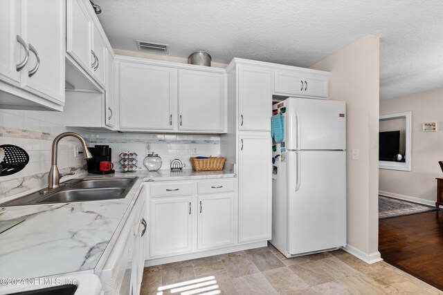 kitchen featuring white cabinets, white refrigerator, sink, light hardwood / wood-style flooring, and light stone countertops