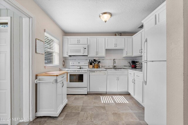 kitchen featuring tasteful backsplash, a textured ceiling, white appliances, sink, and white cabinetry