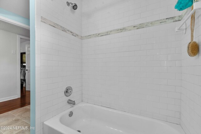 bathroom with wood-type flooring and tiled shower / bath