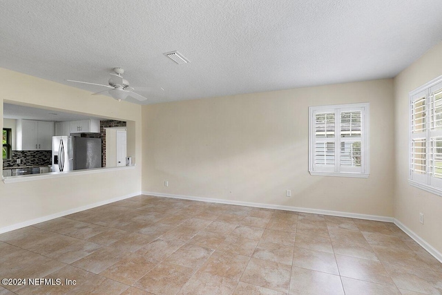 tiled spare room with ceiling fan and a textured ceiling