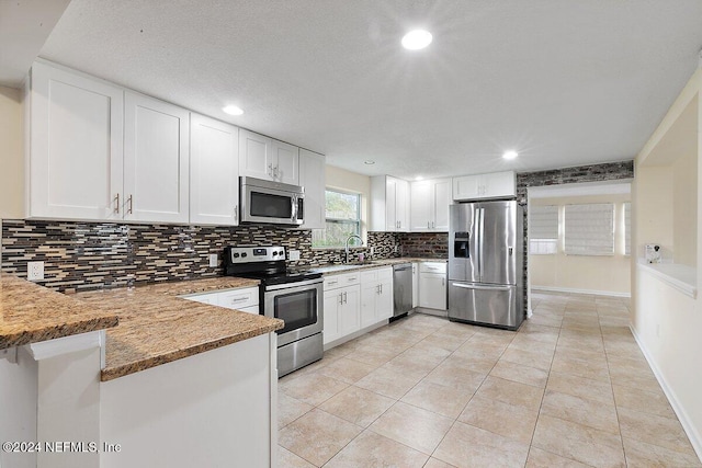 kitchen with white cabinets, sink, decorative backsplash, kitchen peninsula, and stainless steel appliances