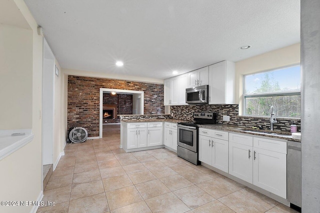 kitchen with sink, stainless steel appliances, white cabinets, kitchen peninsula, and light tile patterned flooring