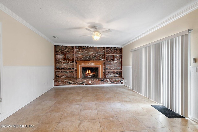 unfurnished living room featuring crown molding, ceiling fan, light tile patterned floors, a textured ceiling, and brick wall