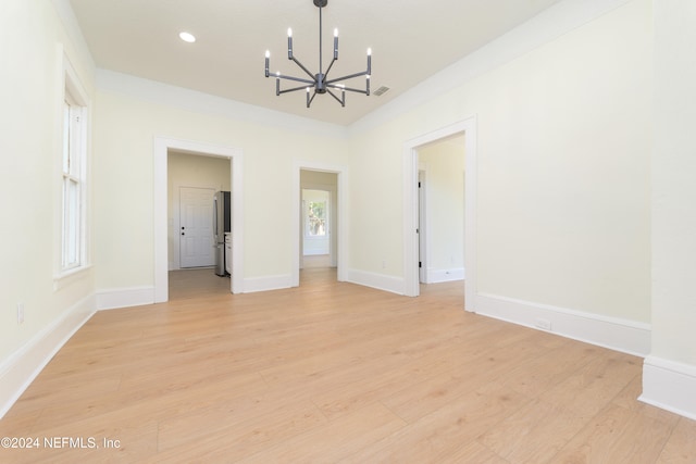 spare room with light hardwood / wood-style flooring and a notable chandelier