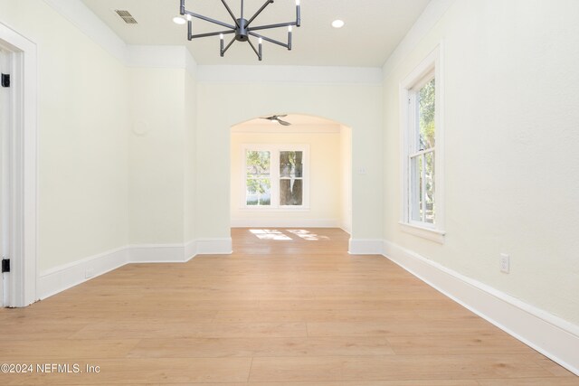 unfurnished room featuring light hardwood / wood-style flooring, a healthy amount of sunlight, and a notable chandelier