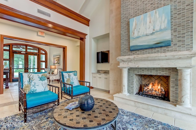 living area featuring a high ceiling, a large fireplace, light tile patterned floors, and french doors