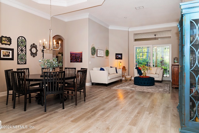 dining room featuring wood-type flooring, crown molding, and an inviting chandelier